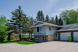 a blue house with a driveway and trees at Pine in Appleton