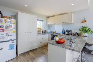 uma cozinha com armários brancos e um frigorífico branco em Apartment style Beach House. Birdlings Flat em Little River