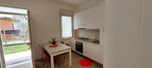 a kitchen with white cabinets and a table and a window at MariGarda Apartments in Assenza di Brenzone