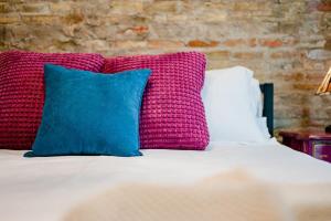 una cama con almohadas coloridas encima en ᴘɪɴʙᴀʟʟ ᴘᴇɴᴛʜᴏᴜꜱᴇ, en Appleton