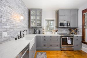 a kitchen with gray cabinets and a brick wall at Historic Heritage Haven in Appleton
