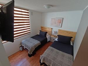 een slaapkamer met 2 bedden en een raam bij Cómodo Departamento 3 Habitaciones - 1E - Sector Sur in Antofagasta