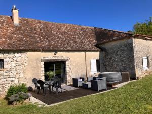 a stone building with a patio with a table and chairs at Périgourdine avec spa et vue in Pomport