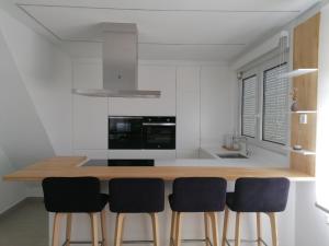 a kitchen with a wooden counter with four chairs at O lar da Tia Carmen in Neaño