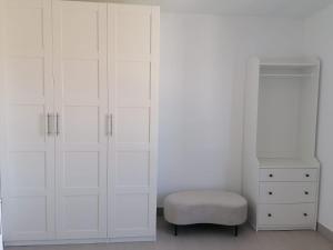 a white bedroom with white cabinets and a stool at O lar da Tia Carmen in Neaño