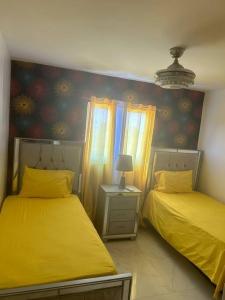 duas camas num quarto com lençóis amarelos em Acogedor Sweet Apartament em Santiago de los Caballeros