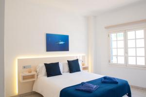 プラヤ・ブランカにあるBlancazul Alto Brisaのベッドルーム1室(白いベッド1台、青いシーツ付)、窓が備わります。