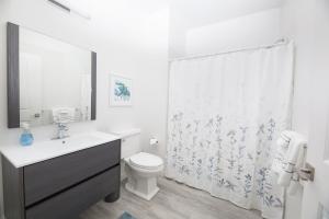 a white bathroom with a toilet and a shower curtain at Sonoma Grove Suites in Sonoma