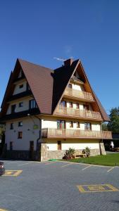 duży budynek z brązowym dachem i parkingiem w obiekcie Kwatery Prywatne Beata Marek w mieście Białka Tatrzanska