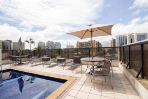 un patio avec une table, des chaises et un parasol dans l'établissement Charmoso e central, à Brasilia