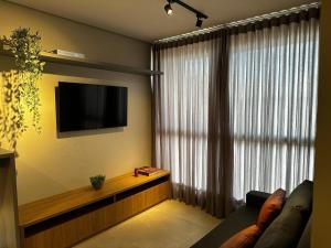 a living room with a couch and a tv and a window at PARK SUL - Edifício Essence - 6 in Brasilia