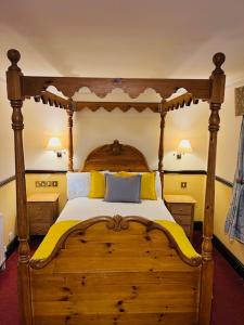 a bedroom with a wooden bed with yellow and blue pillows at Crown & Cushion Hotel in Chipping Norton