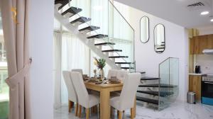 uma sala de jantar com uma mesa com cadeiras e uma escada em Meadow 3BR Transit Modern Duplex Masdar City em Abu Dhabi