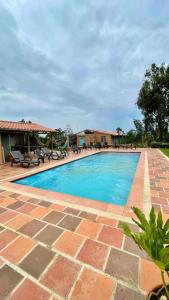 una piscina en un patio de ladrillo con sillas y mesas en Cabaña en la Mesa de los Santos, en Piedecuesta