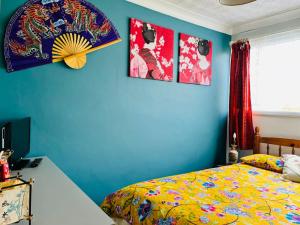 a bedroom with blue walls and a bed with a yellow bedspread at Oriental Belle Aire in Hemsby