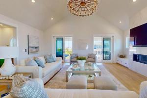 a living room with white furniture and a chandelier at Oceans 12 in Wrightsville Beach