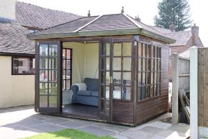 a wooden gazebo with a couch in it at Malthouse Farm Cottage Studio in Dilhorne