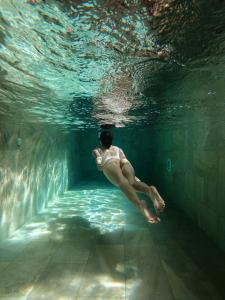 a woman is swimming in a swimming pool at Loft con piscina privada climatizada a 5' del Museo Dalí in Figueres