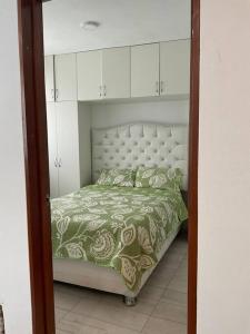 a bedroom with a bed with a green and white comforter at Disfruta de Mollendo in Mollendo