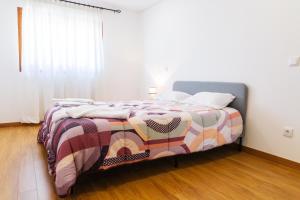 Un dormitorio con una cama con una manta de colores. en CASA PAMPA, en Ribeira de Pena