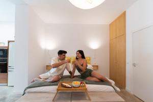 un hombre y una mujer sentados en una cama bebiendo zumo de naranja en Loft con piscina privada climatizada a 5' del Museo Dalí en Figueres