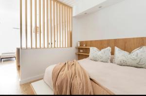- une chambre avec un lit blanc et une tête de lit en bois dans l'établissement Boutique Apartament Torreón, à Mar del Plata