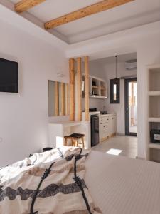 a white bedroom with a bed and a kitchen at Alonia Suites in Naousa