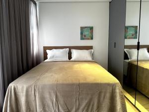 um quarto com uma cama grande e almofadas brancas em PARK SUL - Edifício Essence - 10 em Brasília