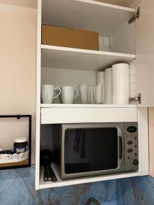 - un four micro-ondes dans un meuble blanc avec des tasses et de la vaisselle dans l'établissement cozy central apartment in the middle of Wiener Neustadt - RMI 2, à Wiener Neustadt