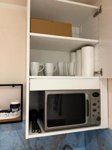 a microwave in a white cabinet with cups and dishes at Innenstadtwohnung in Sackgasse mit Klima - RMI 2 in Wiener Neustadt +4 photos
