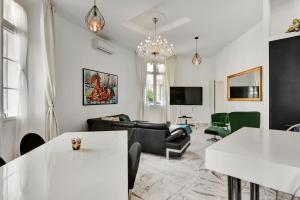 Elle comprend un salon doté d'un mobilier blanc et d'un lustre. dans l'établissement Le Borniol, splendid 3 bedrooms Appt, Cannes Center, à Cannes