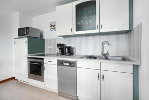 Hellenhahn-Schellenbergにある8 Bett Ferienwohnung Spatzennestの白いキャビネットとシンクのあるキッチン