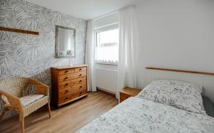 um quarto com uma cama, uma cómoda e um espelho em Ferienwohnung Spatzennest em Hellenhahn-Schellenberg