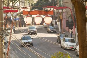 a busy city street with cars parked on the road at Casa na Liberdade by OBA in São Paulo