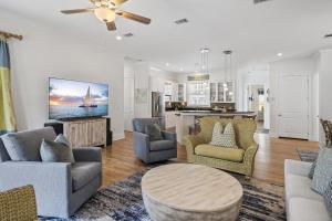 a living room with a couch and chairs and a tv at My Blue Heaven in Rosemary Beach