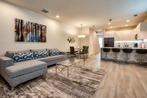 sala de estar con sofá, mesa y cocina en Spacious New Modern Retreat, en Orlando