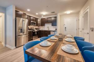 uma cozinha com uma mesa de madeira e cadeiras azuis em Prime Location-Spacious Condo for 8 Guests em Orlando