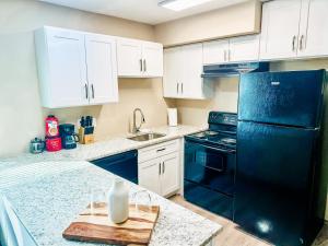 a kitchen with a black refrigerator and white cabinets at Warm Cozy Hideaway Texas City 1 Bed Flat in Texas City