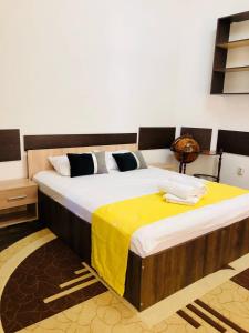 a bedroom with a large bed with a yellow blanket on it at Joy City Stay Unirii19 in Timişoara