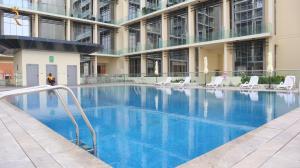 a large swimming pool in a building with chairs at Your Sleek Transit 1BR Oasis Hideaway in Abu Dhabi