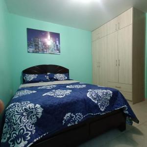 Dormitorio azul con cama con colcha azul y blanca en Pablin, en Trujillo