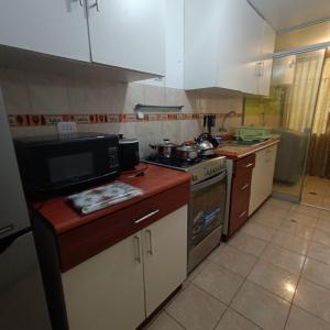 a small kitchen with a stove and a microwave at Pablin in Trujillo