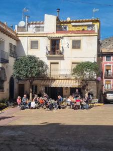 a group of people sitting at tables in front of a building at Casa Plaza Relleu in Relleu
