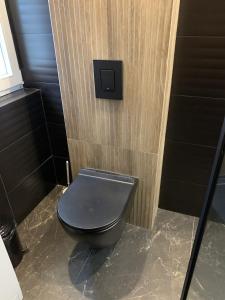 a black toilet in a bathroom with a wooden wall at Apartamenty Astor - Księżycowy in Szczawno-Zdrój