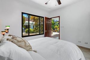 a white bedroom with a large bed and a window at Stylish Home with Chic Decor, Luxury Amenities & Tropical Outdoor Oasis with Sparkling Private Pool in Brasilito +26 photos