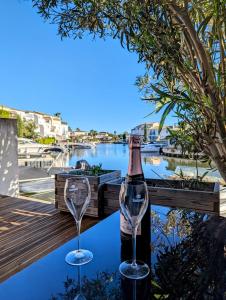 Una botella de vino y dos copas en una mesa. en Belle marina avec ponton et piscine collective, en Aigues-Mortes