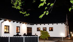 a white house with a black roof at night at Hotel Zum Postkutscher in Cottbus