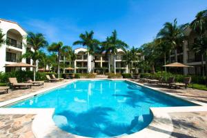 a swimming pool at a resort with palm trees at Classy artsy ocean-view unit near pool at Pacifico in Coco sleeps 6 in Coco