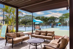 a patio with couches and a tennis court at 3-Bedroom 2-Bath Condo Overlooking Pool in Coco