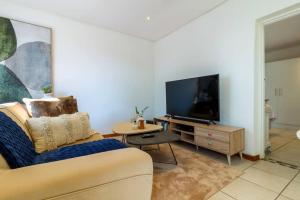 uma sala de estar com um sofá e uma televisão em 1 Bedroom Apartment in Houghton with Uninterrupted WiFi em Joanesburgo